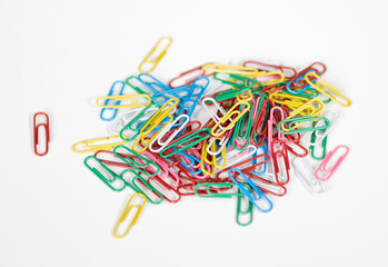 Colourful red, green, blue, pink yellow, white paper clips, piled messily, for business and personal organization, on white background