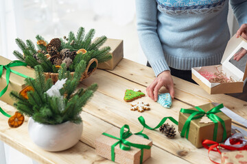 woman in sweater puts cookies, gingerbread, text space, copy space in a box