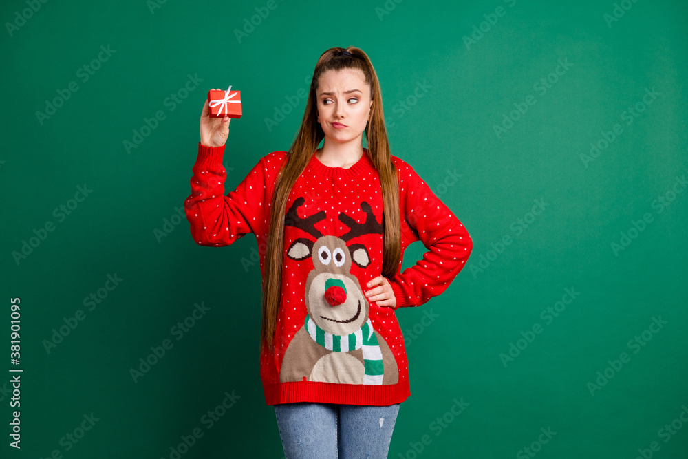 Sticker Photo of disappointed pretty lady hold newyear present little tiny giftbox package not sure it's what she wants wear red ugly ornament deer decor pullover jeans isolated green color background