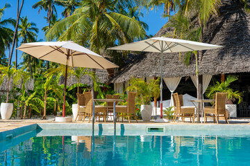 Rest zone near swimming pool on a tropical beach in Zanzibar island, Tanzania, Africa - obrazy, fototapety, plakaty