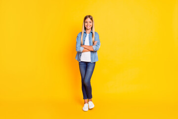 Fototapeta na wymiar Full length body size photo of schoolgirl with straight blonde hair keeping hands crossed isolated on bright yellow color background