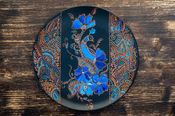 Obraz na płótnie Canvas Decorative ceramic plate with flowers and bird, painted plate on wooden background , dot painting