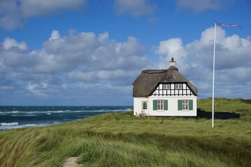altes traditionelles Strandhaus mit Reetdach in Lökken in Dänemark mit Nordsee im Hintergrund
