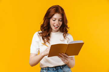 Image of ginger cheerful girl writing in exercise book