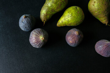 green pears and fig fruits on black shiny backrground