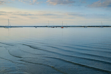 West Wittering, Chichester Harbour, South of England. Small waves gently lap onto the shore in the evening light.