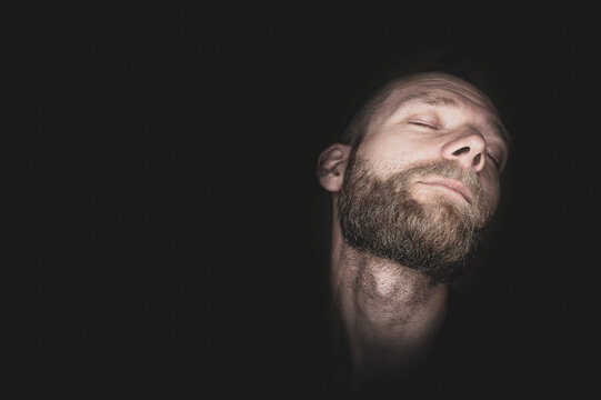 A young man lasciviously pulls his head back and has his eyes closed.