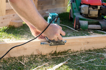 shavings fly when a worker cuts a long wooden board with a router. real worker