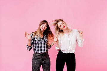 Two carefree female having fun and dancing on pink background. Flash portrait. Party mood ....