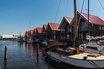 Terherne, Netherlands - April 21 2019: Yachts docked near black wooden dock houses