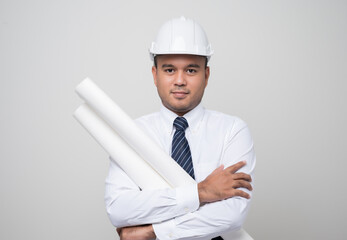 Young handsome asian civil engineer holding paperwork blueprint roll standing post in studio. Worker wearing hard hat on isolated white background..
