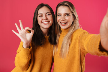 Image of smiling beautiful women showing ok sign while taking selfie