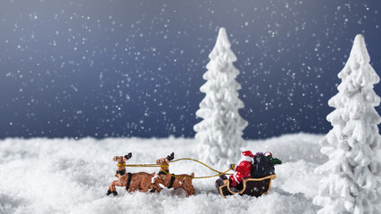 Santa Claus in a sleigh with reindeer in the snowy forest.