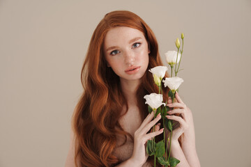 Photo of beautiful redhead shirtless girl posing with white flowers