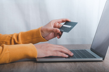 Hand holding credit card and using laptop. Online shopping concept