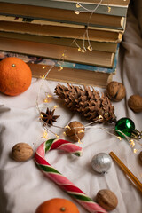 The atmosphere of Christmas and New Year. Big spruce cone, colored candy cane, christmas balls, walnuts and stack of books