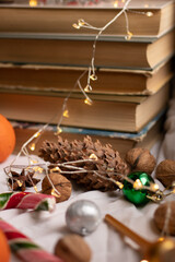 The atmosphere of Christmas and New Year. Big spruce cone, colored candy cane, christmas balls, walnuts and stack of books