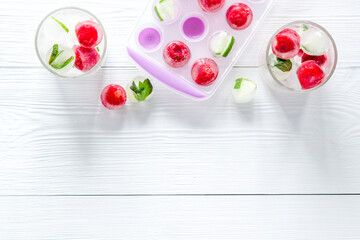 Raspberry and lime in ice cubes on white table top view copy space