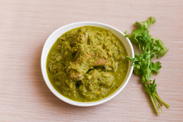 Hariyali chicken curry recipe, hot and spicy Punjabi style dish cooked with spices, spinach, mint, coriander leaves Punjab, India. Top view of North Indian non veg food on white background.