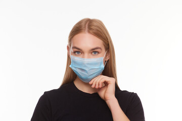 Studio portrait of a girl who holds out a medical mask on her face. Isolated on white background, close up.