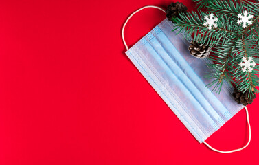 Medical protective mask with branches of Christmas tree on red background. New normal concept