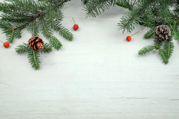 Obraz na płótnie Canvas Christmas decoration with fir branches, pine cones and red berries on wooden board, top view with place for text