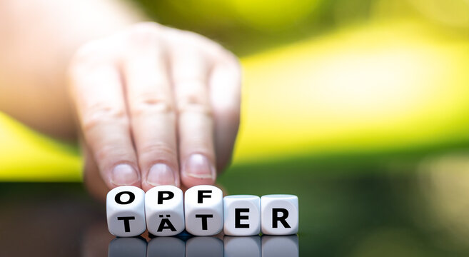 Hand dreht W&uuml;rfel und &auml;ndert das Wort T&auml;tr in Opfer