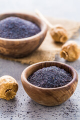 Poppy seeds in small bowl with poppy heads.