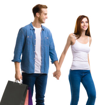 Holiday summer sales, shop, retail, consumer concept - couple with shopping bags, going for purchases, holding hands. Isolated against white background. Studio portrait image. Square composition.