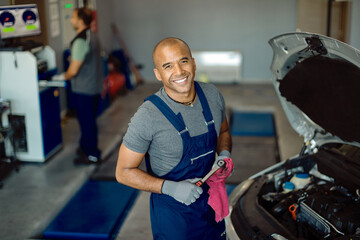 Happy black car mechanic working in repair shop.
