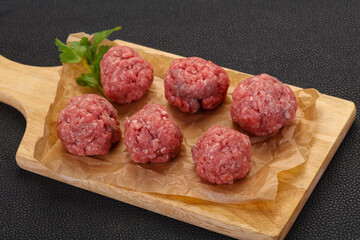 Raw meatball over wooden background