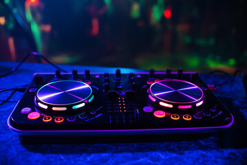 DJ console for mixing music with blurry people dancing at a nightclub party