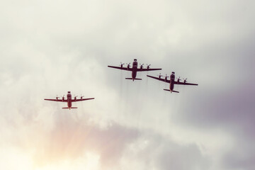 Three turboprop bombers fly in the gray sky.