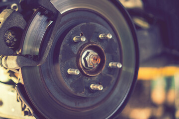 The hub of a wheel in a car service. Suspended car with no wheels. Suspension of car in service room.The car lift up by lifter for maintenance suspension and cleaning parts. Close up. toned