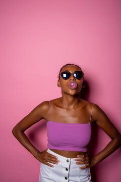 Provocative Black Woman Blowing Bubble Gum - Playful Diverse Young Girl Chewing Gum Isolated On Pink Background