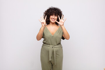  smiling and looking friendly, showing number nine or ninth with hand forward, counting down
