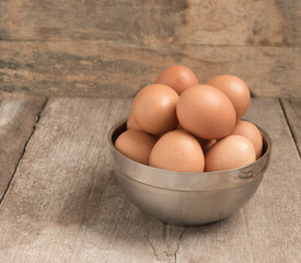 Chicken eggs in cup on wooden table