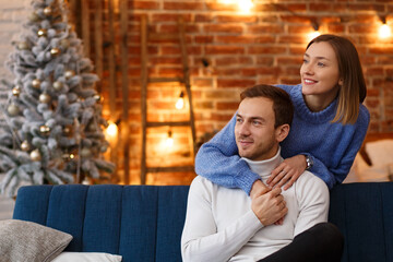 Portrait of beautiful smiling couple hugging at Christmas eve. Beautiful young couple at home enjoying spending time together. Winter holidays, Christmas celebrations, New Year concept.
