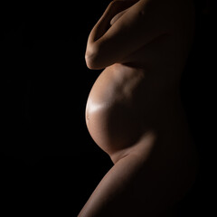 Nude pregnant woman on blak background