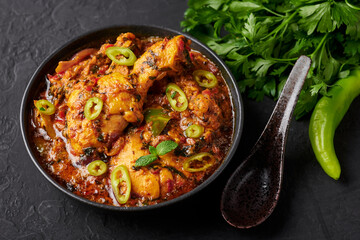 A Chicken Patiala in black bowl on dark slate table top. Murg Patiala is indian cuisine curry dish with chicken meat, spices, curd and cashew nut paste. Asian food and meal.