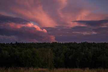 There are dramatic clouds in the dark sky as the sun sets. The sky is dominated by fuchsia, pink.