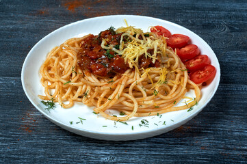 Traditional spaghetti pasta in a plate on a dark background . The view from the top .