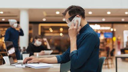 man in protective mask talking on his smartphone