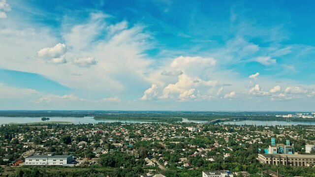 aerial landscape with green city part, big river and beautiful blue sky with white clouds. drone flight over residential city district