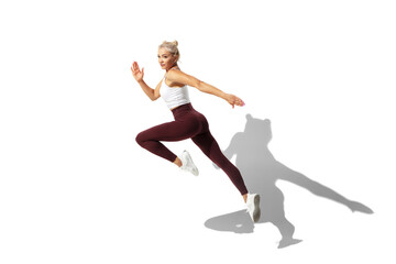 Fototapeta na wymiar Running. Beautiful young female athlete practicing on white studio background, portrait with shadow. Sportive fit model in motion and action. Body building, healthy lifestyle, style concept.