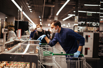 customer in protective gloves choosing products in a supermarket.