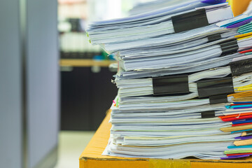 Pile of documents on desk stack up high waiting to be managed