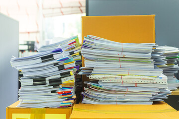 Pile of documents on desk stack up high waiting to be managed