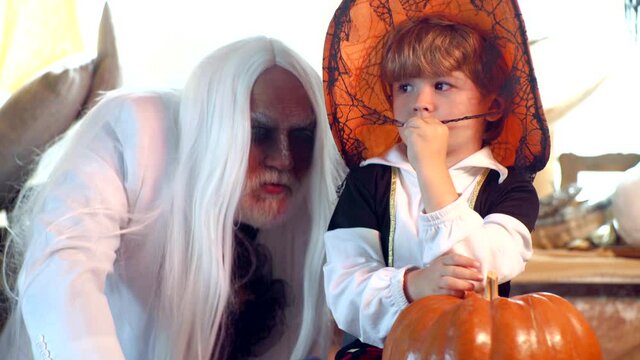 Father and son playing scary Halloween games at home. Grandpa and grandson with pumpkin together as preparation for Halloween.