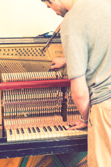Piano tuning process. closeup of hand and tools of tuner working on grand piano. Detailed view of...